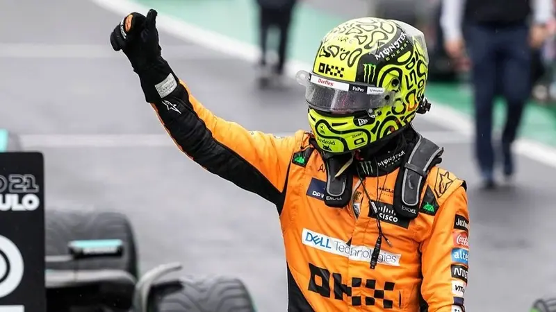 ando Norris wearing a helmet and lifting his hand to the crowd in celebration, showcasing his excitement amid the Monaco Grand Prix betting odds buzz."